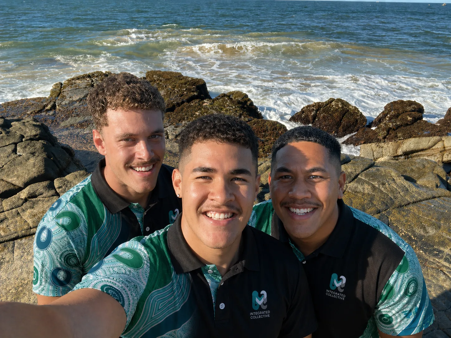 Three Integrated Collective team members smiling together by the ocean